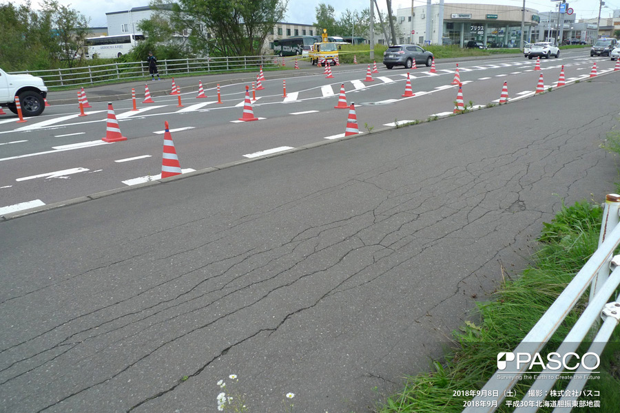 札幌市清田区美しが丘四条７丁目～一条７丁目付近　道路を横断する沈下の状況。路面の沈下が三角コーンの傾きによって明瞭になっている。