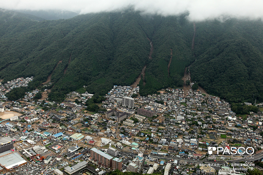 広島県広島市安佐南区八木町　複数の谷で土石流が発生し、土砂が市街地に氾濫堆積している。土石流が発生した渓流では沢沿いに流水が確認できる。